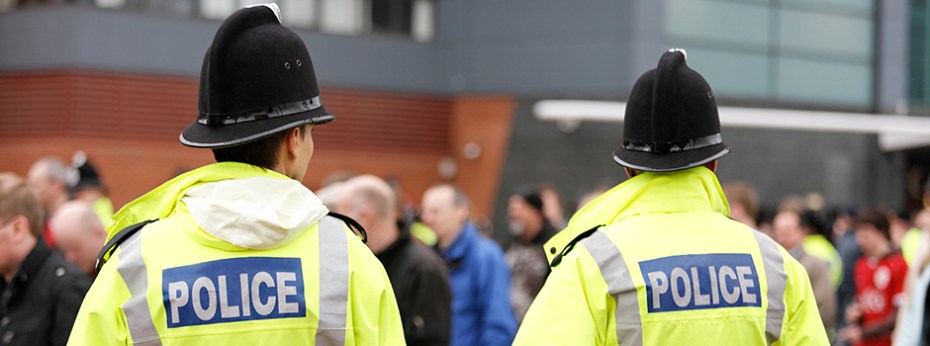 Two Britisih Policemen in Traditional Helmets on Crowd Control